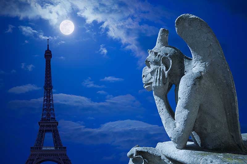 Gargoyle from Notre Dame staring at the Eiffel Tower with a full moon in the night sky.